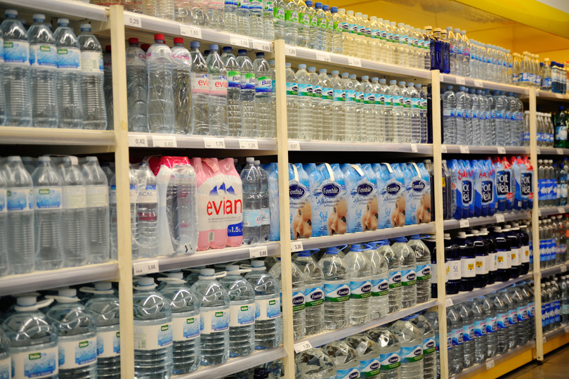 Estantes llenos de agua embotellada a la venta en un supermercado